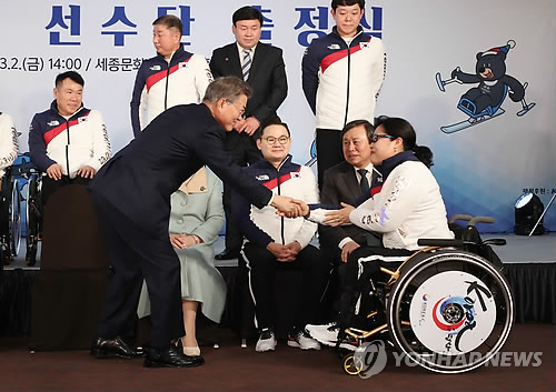 South Korean President Moon Jae-in welcomes an South Korean Paralympics athlete